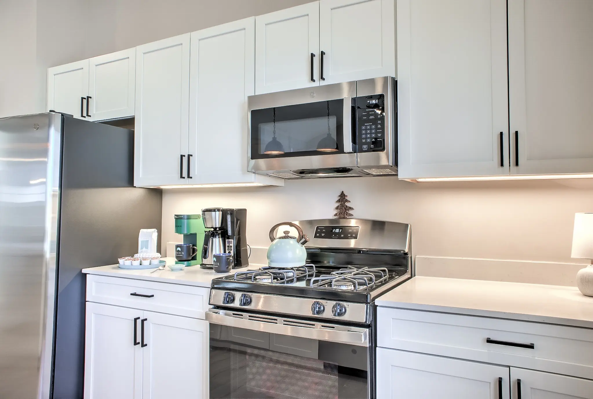 Bright white kitchen with gas range, full-size refrigerator, and generous counter space