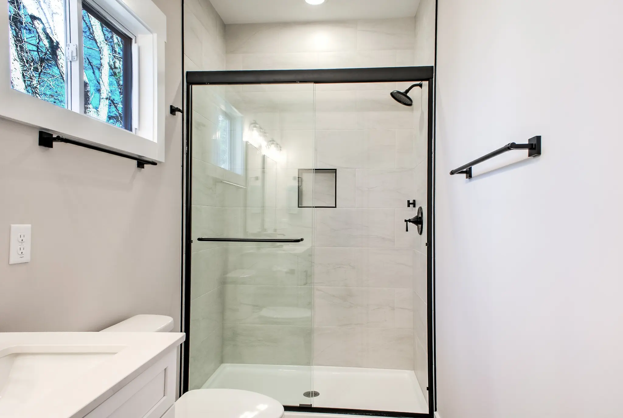 Bright bathroom with glass walk-in shower and matte black fixtures