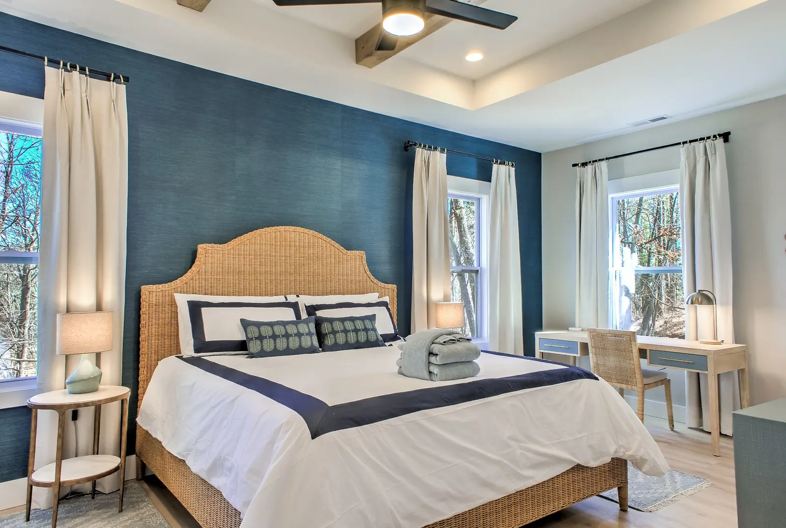Primary bedroom with blue accent wall and woven Serena and Lily bed